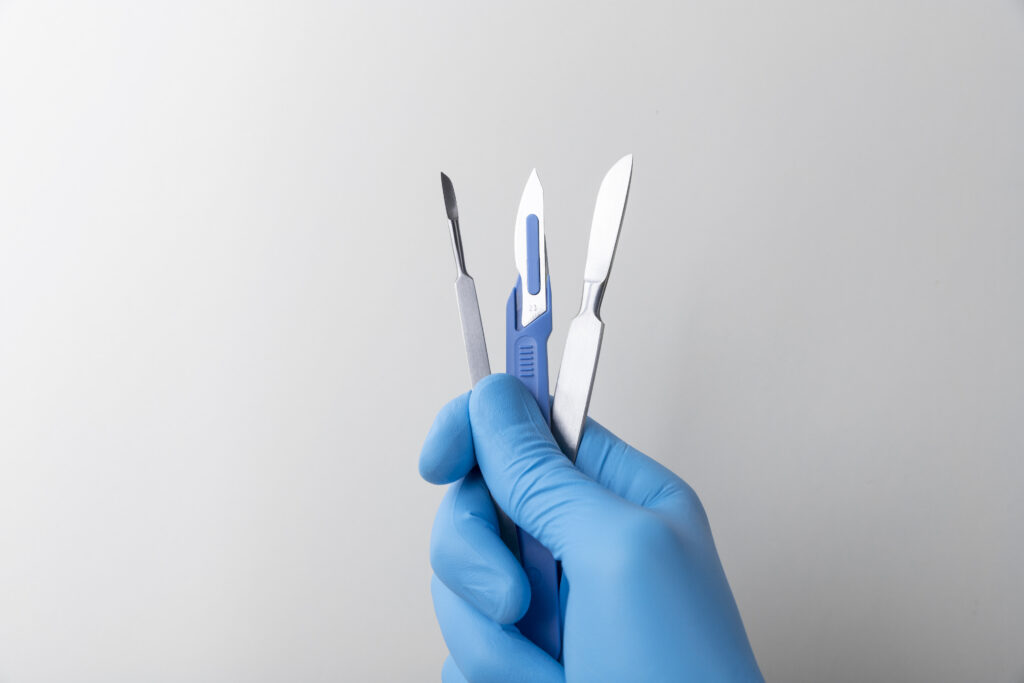 hand-with-rubber-glove-holding-medical-scalpel
